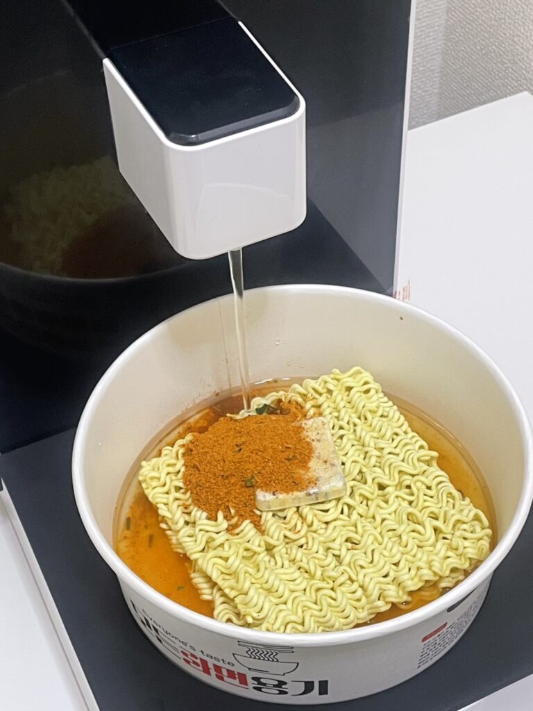 自動調理機がどんぶりにお湯を注いでいるところ